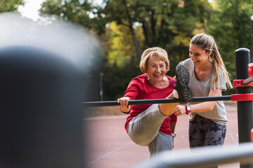 Grandmother and granddaughter training on bars in a park