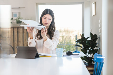 Young woman sitting at table at home holding plane model