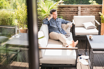 Confident man relaxing on the terrace, reading book