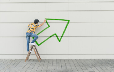 Digital composite of young man drawing an arrow at a wall
