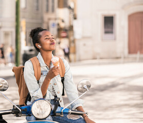 Happy young woman with motor scooter enjoying ice cream in the city, Lisbon, Portugal