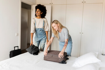 Two smiling women with baggage arriving in accomodation