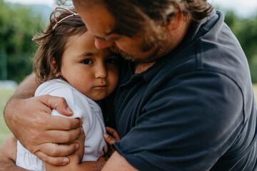Father embracing daughter while sitting at backyard