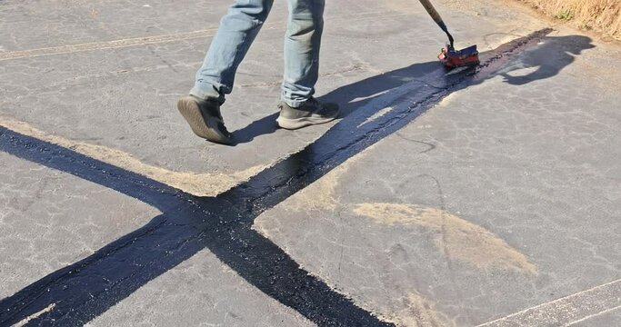 Worker patcher performs coating, crack sealing, bitumen emulsion road surface restoration during workday