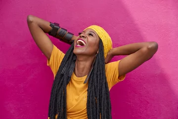 Fotobehang Portrait of woman with long dreadlocks laughing in front of a pink wall © tunedin