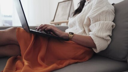 Crop self employed lady using laptop on sofa
