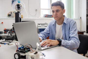 Student setting up 3D printer, using laptop