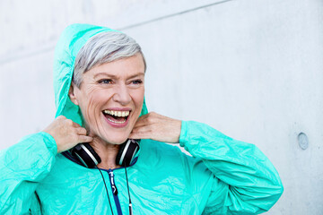 Portrait of laughing sporty mature woman with headphones
