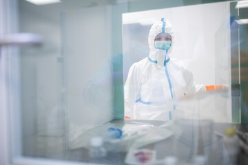 Lab technician wearing cleanroom overall at material sluice