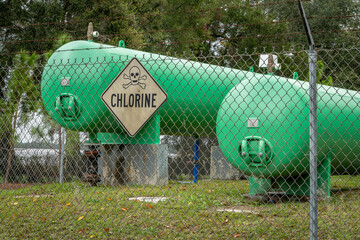 industrial chlorine gas tanks behind a fence with a warning sign