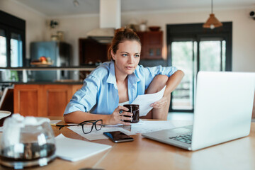 Focused Woman Working from Home with Laptop and Papers