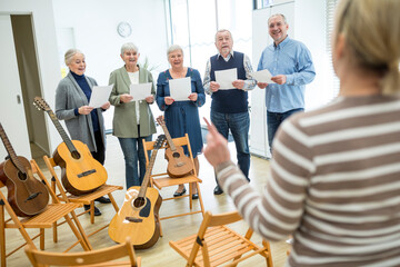 Seniors in retirement home making music singing in choir