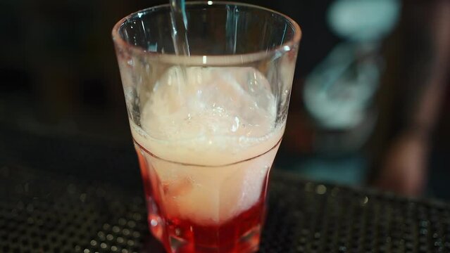 bartender prepare alcohol cocktail drink with red berry liquor, vodka and ice