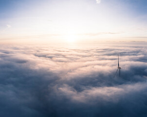 Germany, Aerial view of wind turbine shrouded in clouds at sunrise