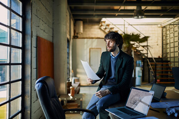 Focused Architect Reviewing Blueprints in Loft Office