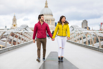 UK, London, young couple walking hand in hand on bridge in front of St Pauls Cathedral