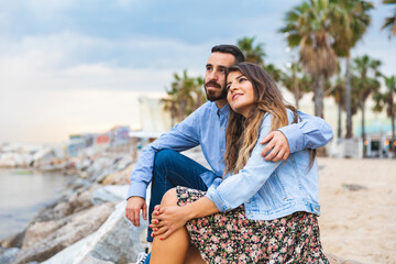 Spain, Barcelona, couple sitting on rocks at the seaside