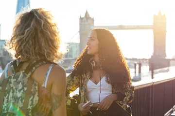 Foto op Canvas UK, London, two friends together in the city with Tower Bridge in background at sunset © tunedin