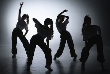 In the shot on a black background in the light of a spotlight in the silhouette. Dance group...