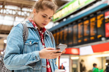 Young woman checking smartphone at the train station