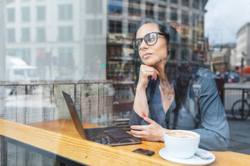 Business woman having a break in a cafe and working with a laptop