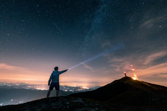Italy, Monte Nerone, silhouette of a man with torch under night sky with stars and milky way