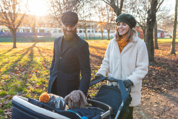Happy couple with little son in a pushchair at park