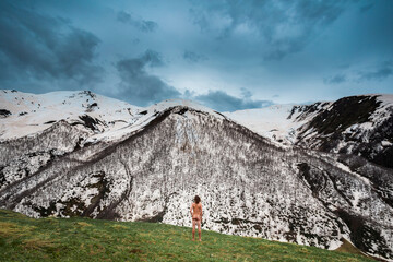 Georgia, Svaneti, Ushguli, Male nudist admiring snowcapped peaks inCaucasus Mountains