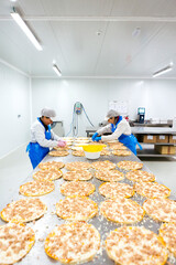 Women preparing pizzas in pizza company