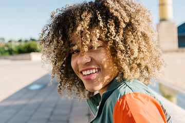 Happy young woman with curly hair during sunny day