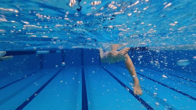 Leg movement (kicking legs ) of the young girl backstroke swimming. Underwater rear view.