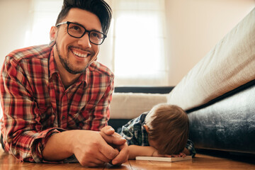 Father and son lying on the floor with a book