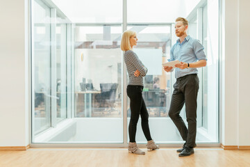 Businessman and woman standing in corridor, talking