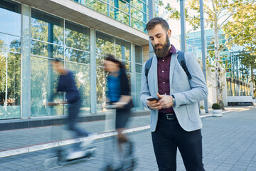 Businessman using cell phone with commuters riding on scooters © tunedin