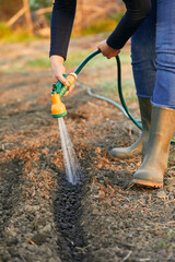 Low section of woman watering with garden hose