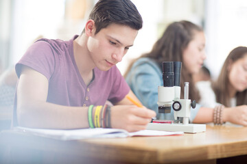 Science student working in class with microscope