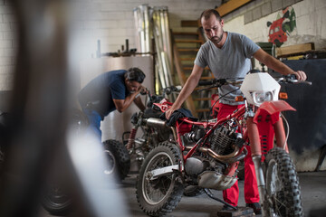 Two mechanics in motorcycle workshop