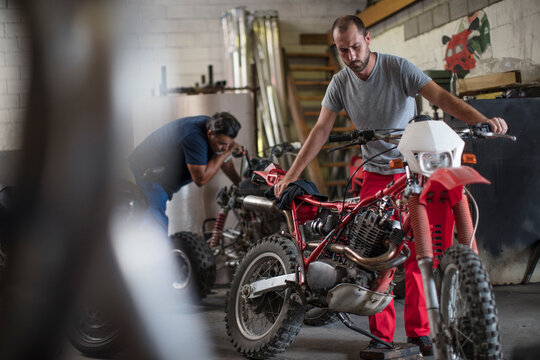 Two mechanics in motorcycle workshop