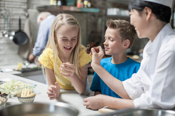 Female chef with girl pulling faces in cooking class