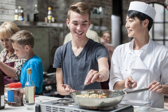 Teenager and female chef cooking together