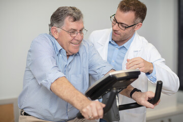 Doctor looking at senior patient on exercise machine