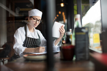 Woman in workwear with clipboard and tablet at the window