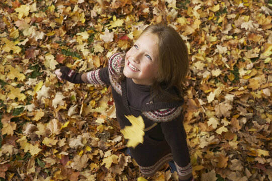 Portrait of Girl Looking at Autumn Leaves in Air