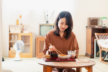 和室でご飯を食べる若い女性