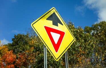 yield sign on road, symbolizing caution and giving way to oncoming traffic, against a clear blue sky
