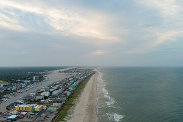 aerial shot of a gorgeous summer landscape along the coastline with people walking and relaxing in the sand, beachfront homes, blue ocean water and waves in Carolina Beach North Carolina USA