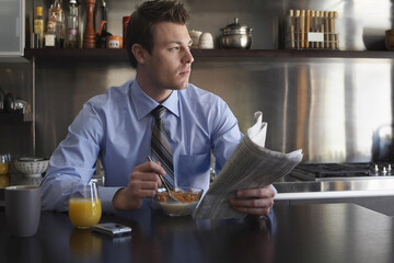 Man Reading Newspaper During Breakfast