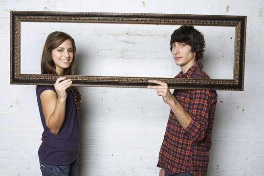 Young Couple Holding Picture Frame