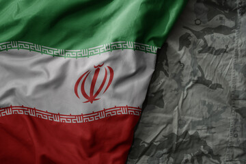 waving flag of iran on the old khaki texture background. military concept.