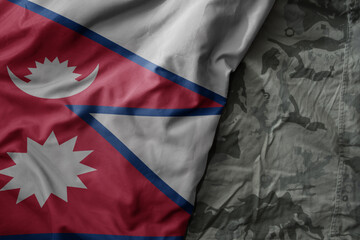 waving flag of nepal on the old khaki texture background. military concept.
